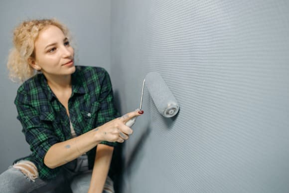 Blonde_Dame_streicht_Wand_mit_grauer_Farbe