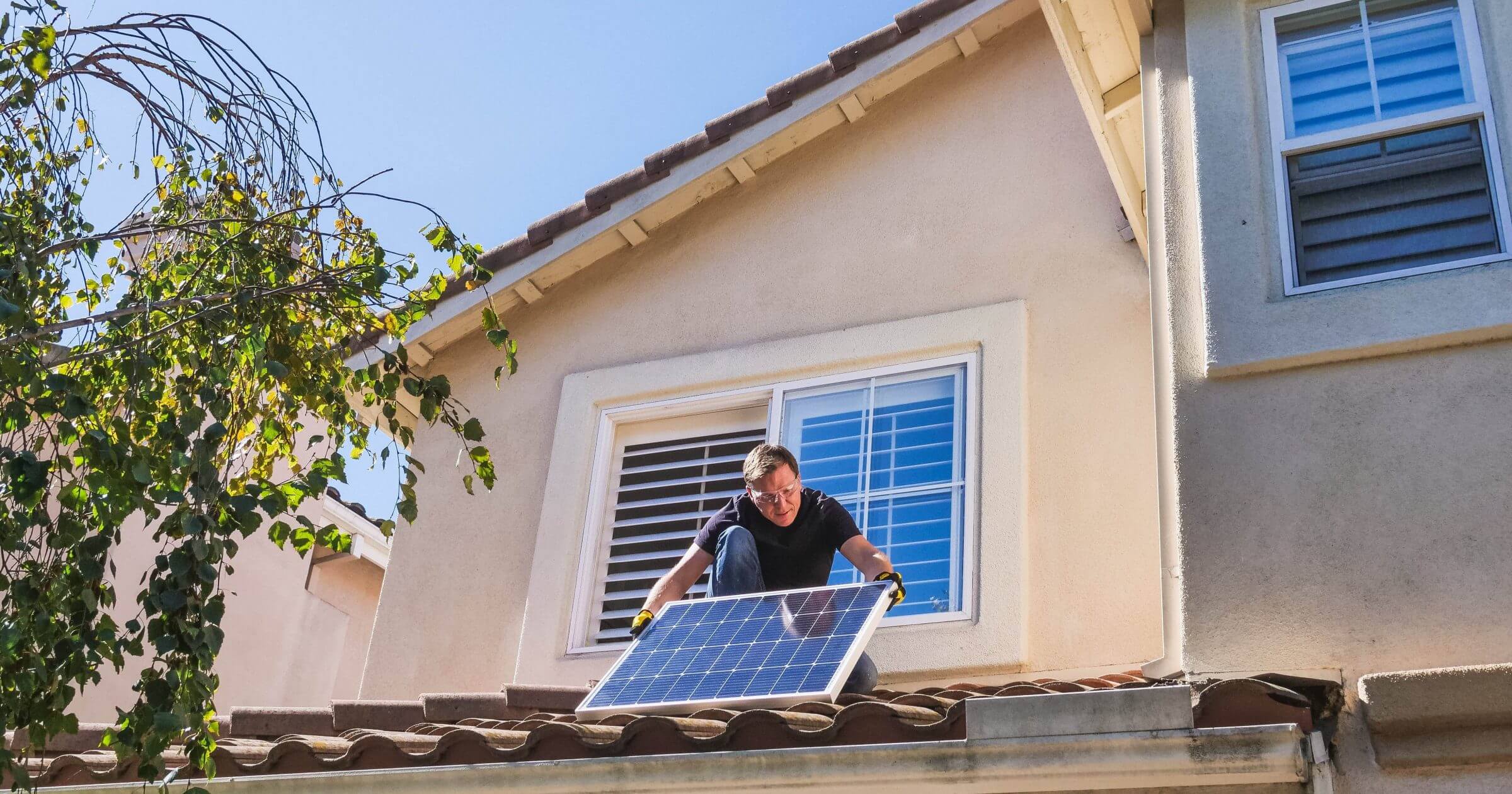 Mann zieht Photovoltaikanlage auf sein Dach - es gilt das Gebäudeenergiegesetz 2024