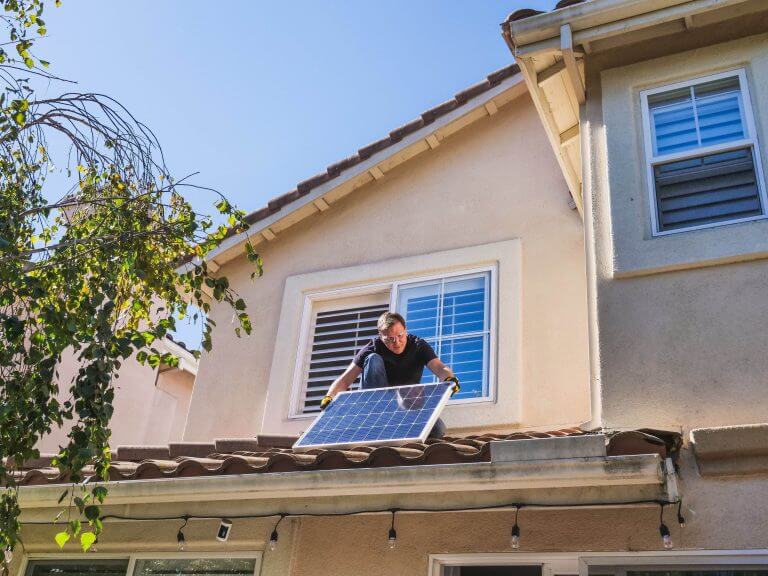 Mann zieht Photovoltaikanlage auf sein Dach - es gilt das Gebäudeenergiegesetz 2024