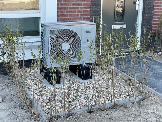 Wärmepumpe im Eingangsbereich eines Hauses mit umgebender Bepflanzung
