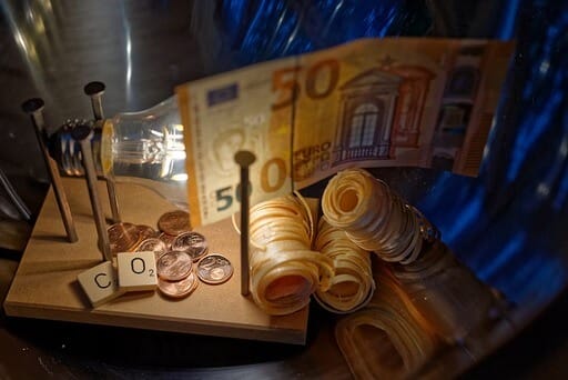 Kaminanzünder, Geld und Glühbirne mit zwei bedruckten Holzplättchen, auf denen sich CO2 ablesen lässt.