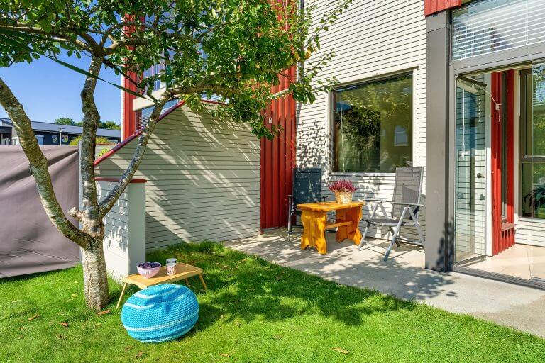 Ein Garten im Erdgeschoss mit zwei Stühlen und einem kleinen Tisch an der Wand unter dem Fenster.