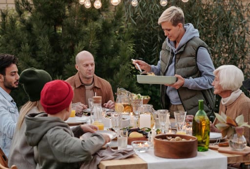 Menschen verschiedener Generationen sitzen am gedeckten Gartentisch. Die familiengerechte Immobilie bietet auch Draußen Platz für alle.