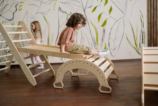 Zwei Kinder spielen in ihrem Zimmer auf Holzmöbeln.