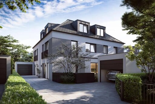 Ein grau-weiß gestaltetes Doppelhaus mit Walmdach und Gauben wird von zwei voneinander separierten Garagen und niedrigen, grünen Hecken flankiert.