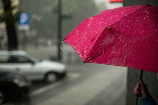 Ein roter Regenschirm auf einer nassen Straße.