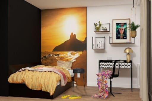 Mikroapartment mit Bett vor Fototapete, daneben eine Wand mit schönen Bildern. 