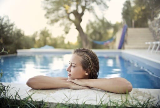 Frau am Pool hat Zeit für die lockere Immobiliensuche.