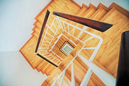 Eine gewundene Holztreppe mit weißem Geländer.