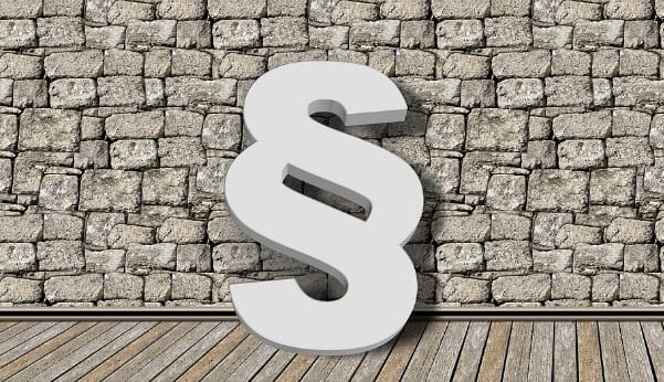 Paragraphenzeichen an einer Steinmauer. Das Schneller Bauen Gesetz kann dem Wohnungsbau einiges an Potenzial bieten.