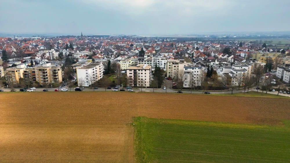 Luftaufnahme einer Ackerfläche neben einer vielbefahrenen Straße am Westrand von Leinfelden-Echterdingen. Im Norden dichte Wohnbebauung.