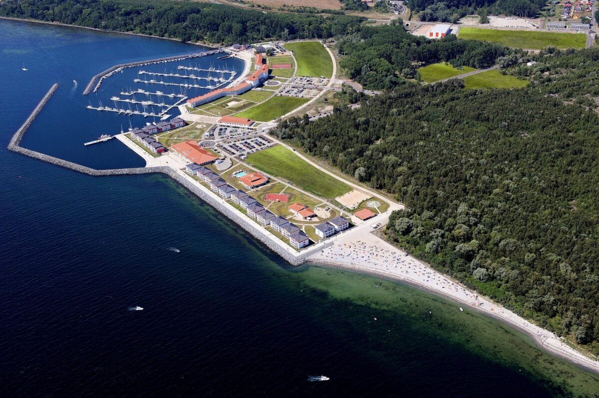 Luftaufnahme des Neubauprojektes. Links der Yachthafen, rechts der Strand, davor die Ostsee.