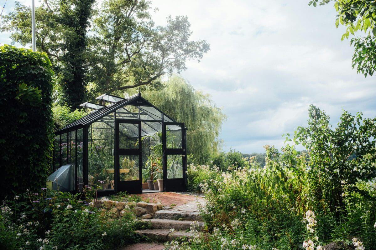 Üppig begrünter Garten mit Gewächshaus.