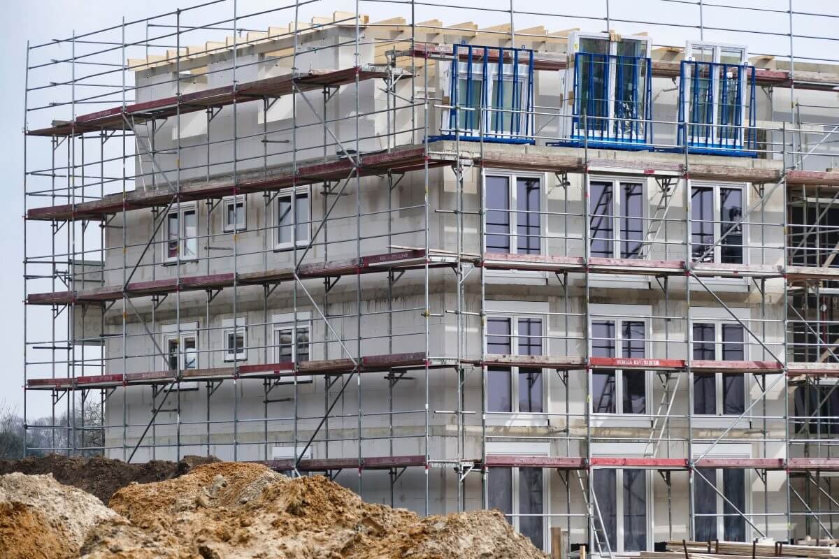 Mehrfamilienhaus im Rohbau. Gerüst vor dem Haus.