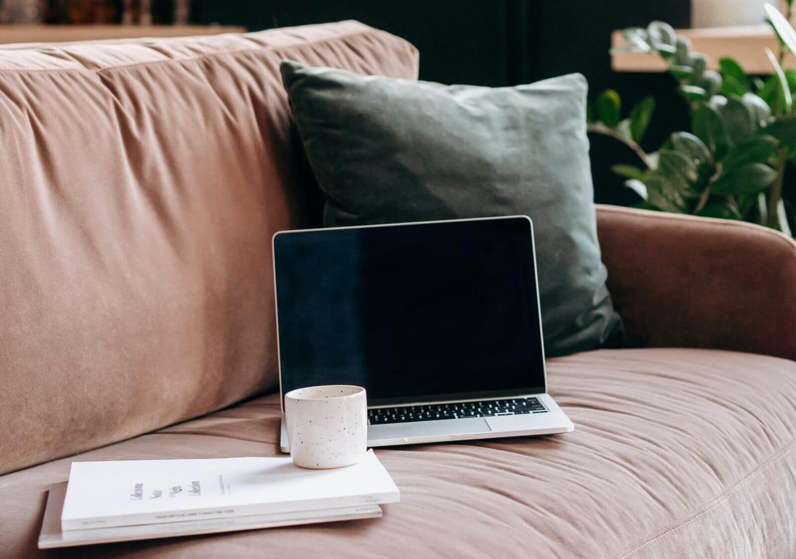 Bequeme Couch mit Laptop, Tasse und Notizbuch – eine Atmosphäre für kreatives Arbeiten oder Entspannung.