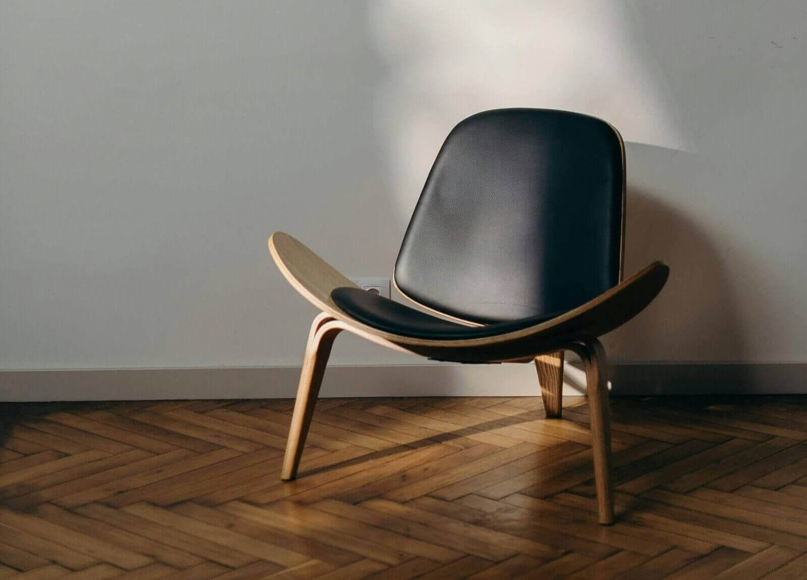 Minimalistisches Zimmer mit einem Designerstuhl aus Holz und Leder als Symbol für eine schlichte Männerwohnung.