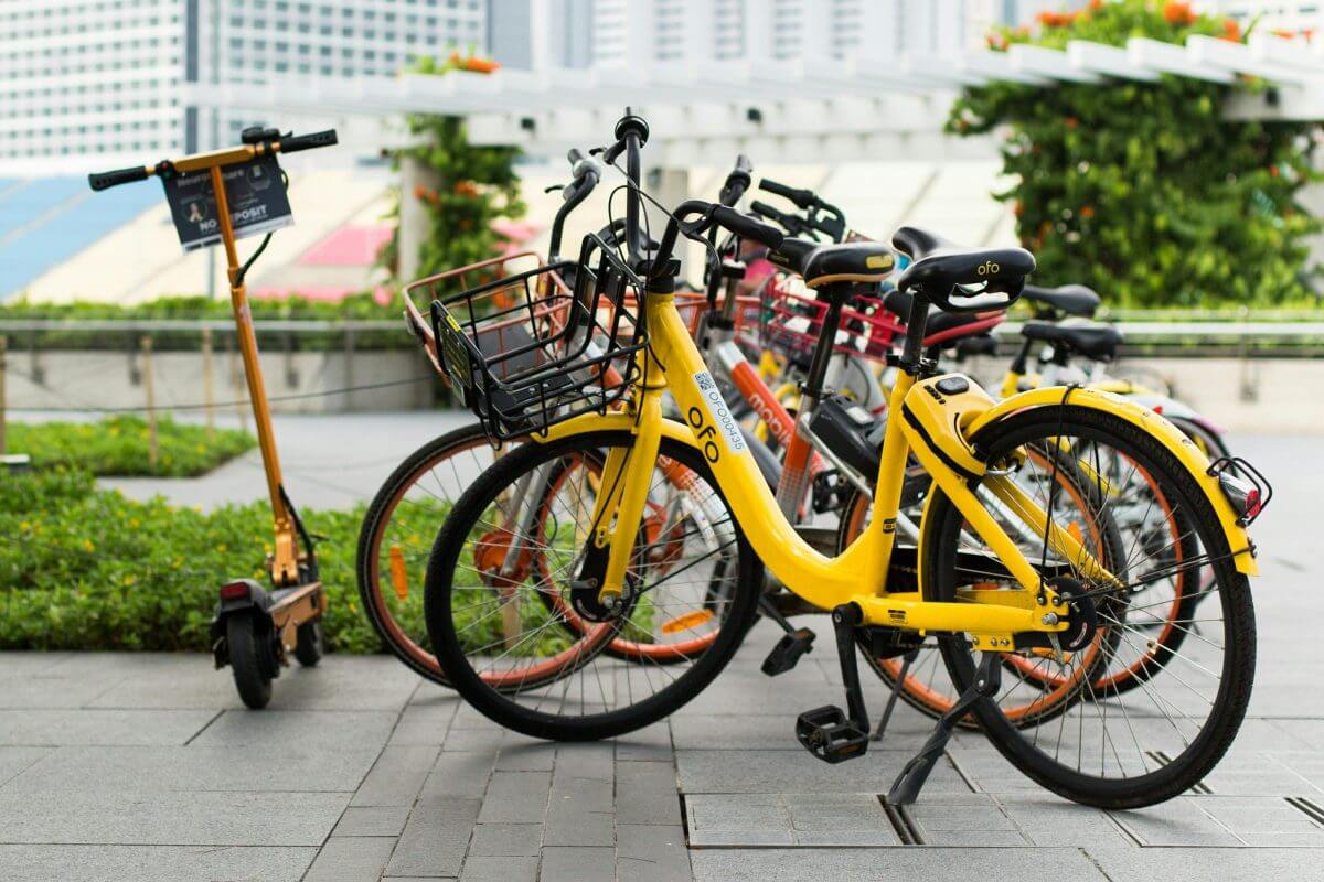 Fahrräder und ein E-Scooter, die nachhaltige Mobilitätslösungen in einem Mixed-Use-Quartier repräsentieren, stehen in einer urbanen Umgebung.