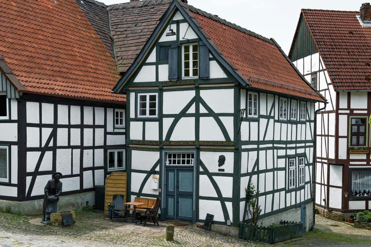 Historisches Fachwerkhaus mit rotem Ziegeldach und kleiner Sitzgruppe vor der Tür.