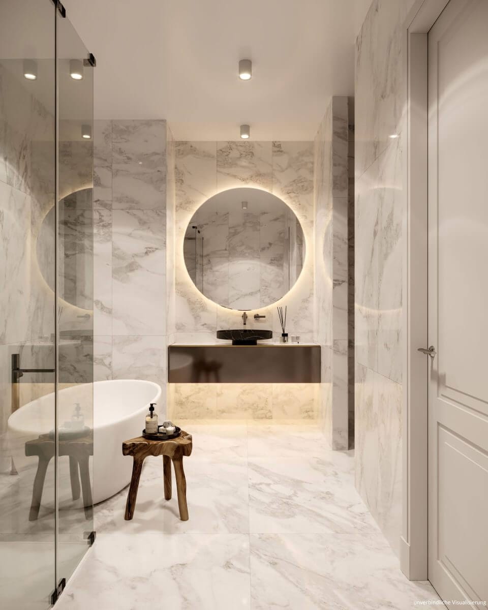 Ein edles Neubau-Bad mit Naturstein, beleuchtetem großen Spiegel und einer Badewanne.