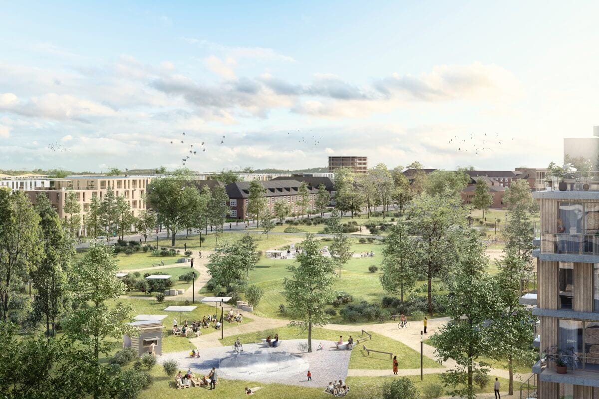 Der Nordpark im Quartier Krampnitz mit weitläufigen Wiesen, Bäumen, Spiel- und Aufenthaltsbereichen. Im Hintergrund moderne Wohngebäude und historische Backsteinbauten.