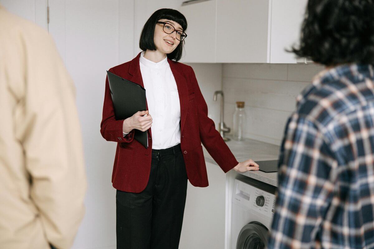 Frau steht mit zwei Personen neben der Waschmaschine.jpg